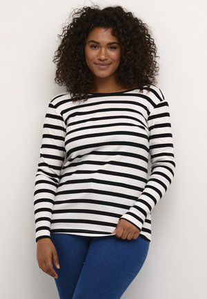 Black and white striped long-sleeve top with a round neckline, made of ribbed fabric, paired with blue jeans.