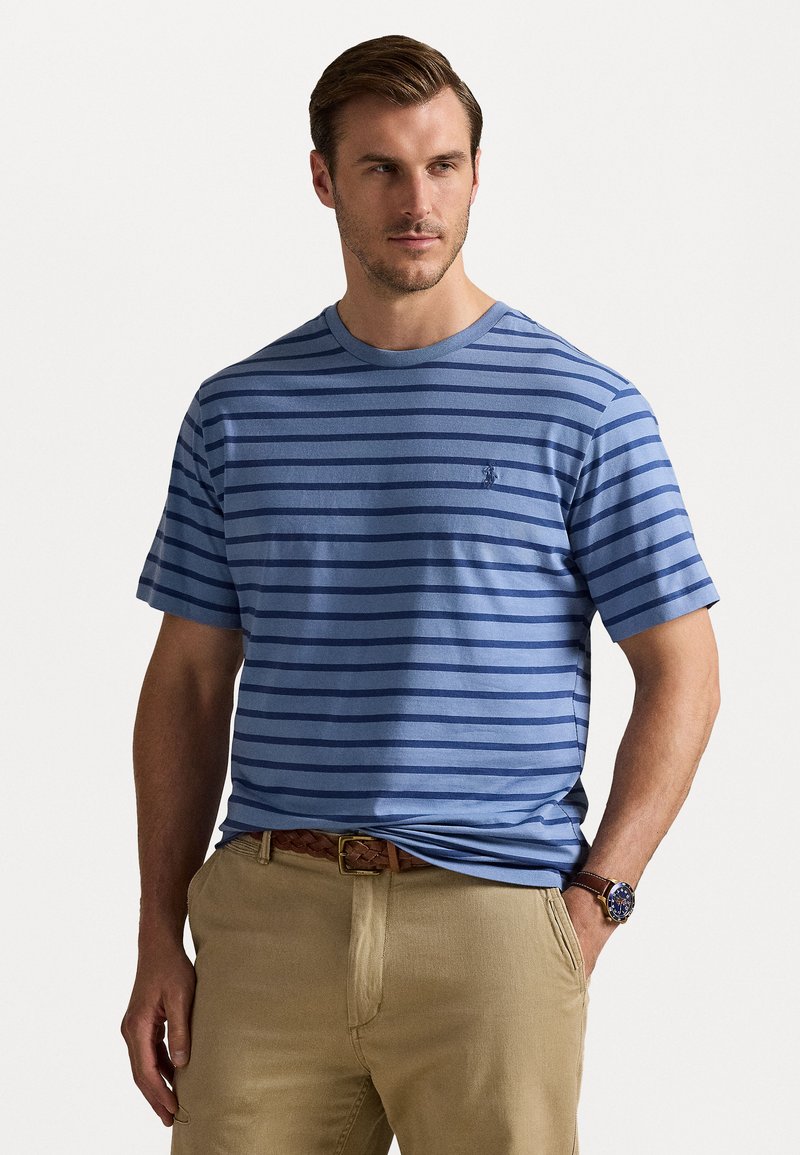 Tricou scurt cu mânecă, cu dungi albastre, fabricat dintr-un material moale, având guler rotund și un logo mic pe piept, asortat cu pantaloni bej.