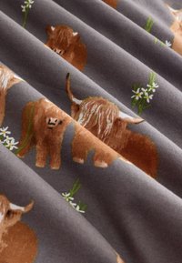 Bomuldsstof med gentaget mønster af brune højlandskvæg og kalve på en grå baggrund, fremhævet af grønt græs og hvide blomster.