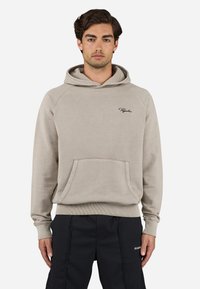 Felpa beige con cappuccio regolabile, tasca frontale e polsini a coste. Presenta una grafica minimale in nero. Tessuto morbido, design casual.