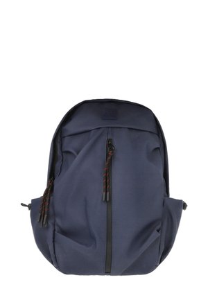 Mochila azul marino hecha de tela duradera, con un zipper frontal y tiradores con acentos rojos, además de bolsillos laterales. Textura suave, forma redondeada.