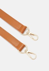 Ruskea nahkainen hihna kullanvärisillä metallisilla klipseillä. Ominaisuuksina sileä pinta ja ompelusyksityiskohdat reunoilla. Kaksi säätömahdollisuutta kiinnityspisteisiin.