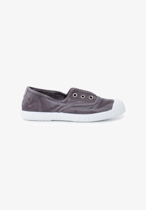 Zapato slip-on de lona gris con suela de goma blanca y punta reforzada. Presenta ojales en los lados y un revestimiento texturizado para mayor agarre.