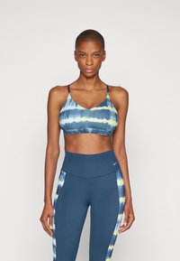 Sutiã desportivo multicolorido com efeito tie-dye, com decote em forma de gota e alças finas, emparelhado com leggings azuis de cintura alta com detalhes em efeito tie-dye nas laterais.