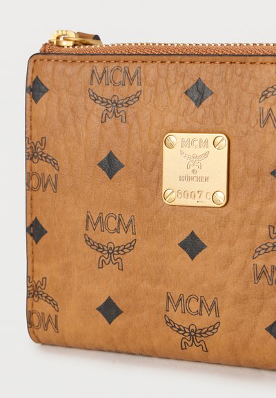 Καφέ πορτοφόλι από δερμάτινη υφή με μαύρα λογότυπα, χρυσή μεταλλική λεπτομέρεια με το όνομα της μάρκας και φερμουάρ κλεισίματος.