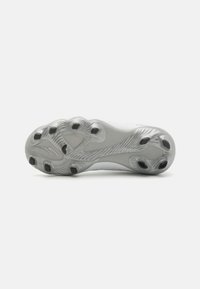 Football shoe sole featuring a textured surface with molded studs in black, designed for traction on grass and turf. Predominantly white with grey accents.