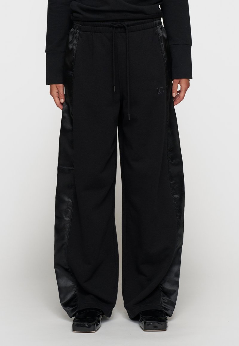 Zwarte sweatpants met satijnen zijpanelen, voorzien van een elastische tailleband, een trekkoord en een numeriek logo op de voorkant.