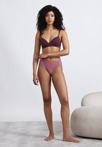 Σουτιέν και σλιπ με ψηλή μέση σε σκούρο βουργουνδί και μωβ. Το σουτιέν έχει σχεδιασμό με λαιμόκοψη σε σχήμα V· τα σλιπ έχουν απαλό φινίρισμα με λεπτή άκρη.