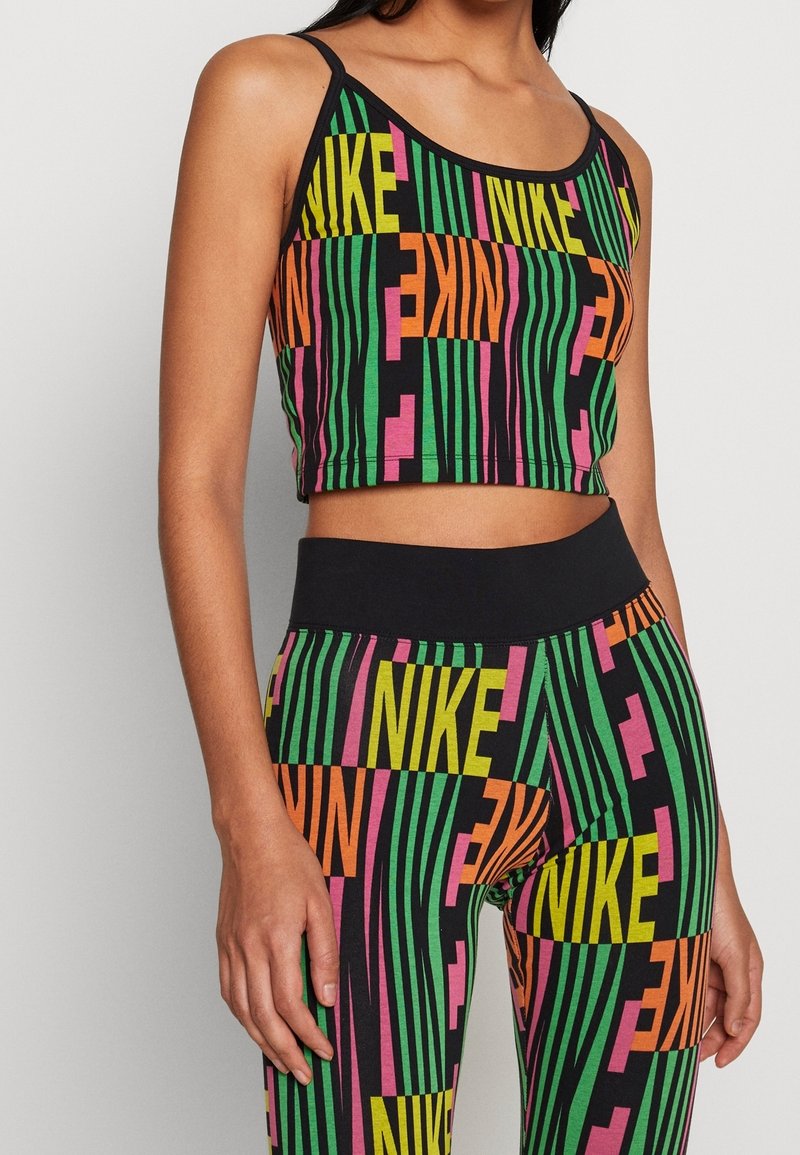 Czarny crop top i legginsy z wyrazistym, wielokolorowym napisem "NIKE" w zielonym, różowym i żółtym kolorze oraz pionowymi paskami. Elastyczny materiał.
