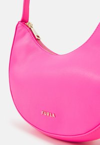 Růžová kožená taška přes rameno s zakřiveným tvarem, vybavená zlatým zipem a na přední straně raženým zlatým názvem značky "FURLA".