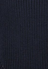 Tmavě modrá pletená látka s texturovaným žebrovaným vzorem, se stejně rozloženými vertikálními pruhy a jemnou, elastickou kvalitou.