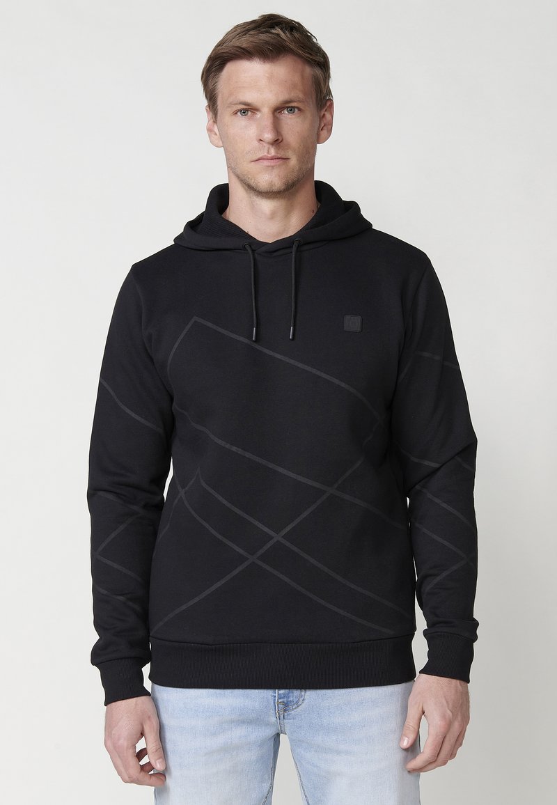 Hanorac negru cu un model geometric texturat. Are un glugă cu șnur și manșete cu elastic. Materialul pare moale și elastic.