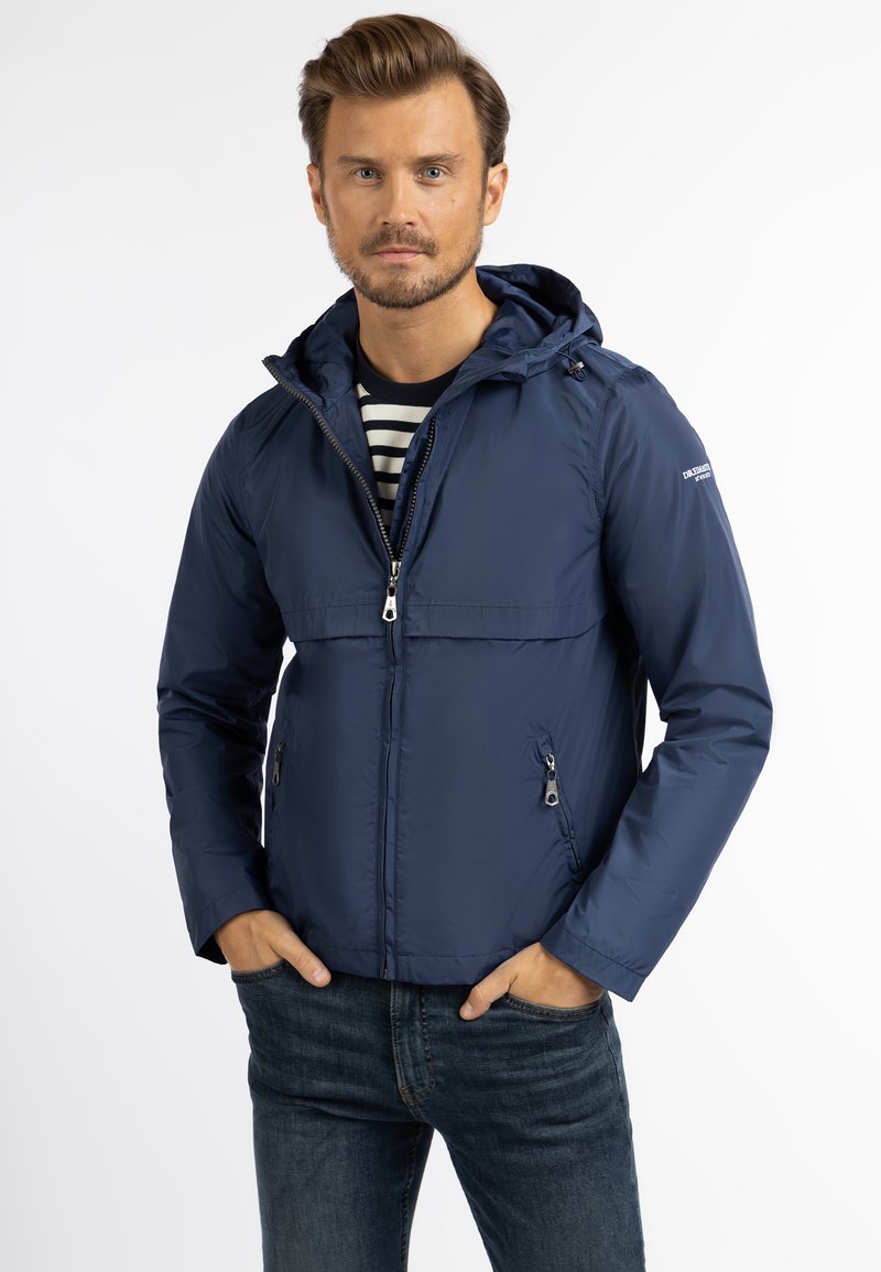 Marineblauwe jas met capuchon, met rits aan de voorkant en twee zijzakken. Glad, lichtgewicht materiaal met een minimalistisch ontwerp en geen zichtbare patronen.