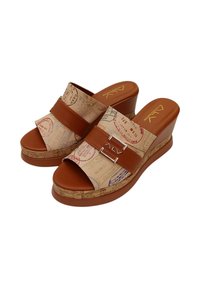 Bruine sleehakken met een zool van kurkachtig materiaal en een bovenwerk met een reistenthema en stempels, twee brede bandjes en metallic accenten.