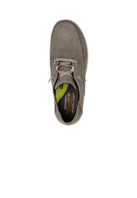 Zapato de tela gris con una superficie texturizada, puntera redondeada, cierre de cordones en la parte delantera y plantilla de espuma viscoelástica. Presenta un forro interior de color verde brillante.