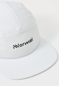 White cap made of lightweight fabric with a smooth texture. Features a flat brim and black "Normal" logo on the front.