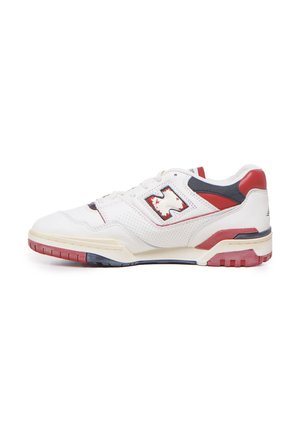 Zapatilla deportiva blanca con cuero perforado, acentos en rojo y azul marino, cuello acolchado y una suela de goma texturizada con un diseño multicolor.