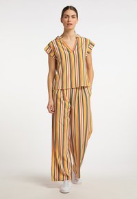 Gestreifter Zweiteiler mit kurzärmligem Oberteil und weit geschnittenen Hosen in Gelb, Orange, Grün und Pink. Hergestellt aus leichtem Stoff.