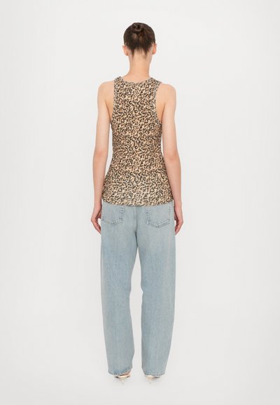 Haut sans manches à imprimé léopard associé à un jean léger et ample de couleur bleu clair ; la tenue affiche une silhouette décontractée et un tissu texturé.