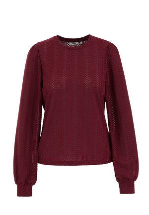 Bordo blūze ar garām, uzpūstām piedurknēm. Izgatavota no teksturētas auduma ar zigzagveida rakstu. Apaļa kakla līnija un pieguļoši aproces.