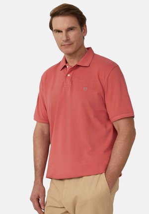 Polo de couleur corail, à manches courtes et col, avec trois boutons au cou et un logo subtil sur la poitrine.