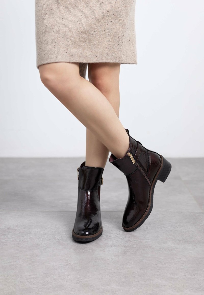 Botines burdeos de cuero brillante, con cremallera lateral, punta redonda y un tacón corto de bloque.