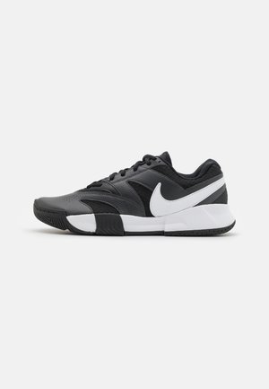 Baskets athlétiques noires et grises avec logo Nike Swoosh blanc et semelle intermédiaire blanche, vues de profil sur fond uni.