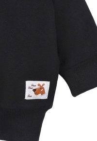 Czarny sweatshirt z krótkimi rękawami z białą metką przedstawiającą rysunkowego psa z napisem "How How How" na czerwono. Miękki materiał bawełniany.