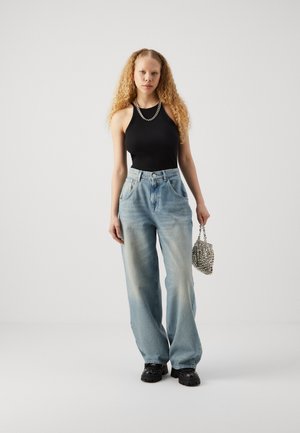 Svart ribbad linne, ljusblå vida jeans med framfickor, silverkedja halsband, och en silverpärlhandväska; svarta plattformsskor.