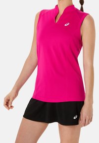 Top atlético sin mangas en fucsia con un cuello alto, combinado con una falda negra. Presenta un pequeño logo blanco en la parte superior y en la falda.