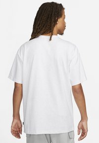 Witte T-shirt met korte mouwen, voorzien van een ronde halslijn en een ontspannen pasvorm. De stof lijkt zacht, zonder zichtbare patronen of accenten.