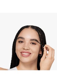 Zwart gevlochten haar met een gladde afwerking, terwijl een mascara-achtig product wordt aangebracht met een slank, cilindervormig penseel. Lichte, neutrale achtergrond.