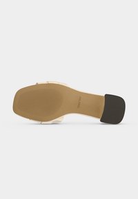 Semelle de sandale avec un bout carré, semelle beige clair, bout de talon noir et nom de la marque ALDO embossé près de la voûte plantaire.