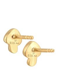 Guld-tonet stud øreringe med en flydende, abstrakt form. Fremstillet af 925 sølv, med en tekstureret overflade og nålelukning.