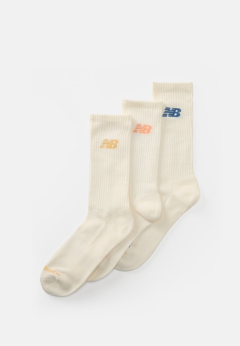 Meias de cor creme com um design canelado. Apresentam logótipos bordados em laranja e azul. Conjunto de três pares em comprimentos variados.