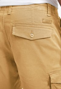 Khaaki cargo šorts s stražnjim džepom koji ima zatvaranje na gumb i šivane detalje, izrađeni su od izdržljive mješavine pamuka.