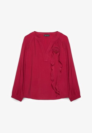 Rød langærmet bluse med V-udskæring, rynkede ærmer og dekorativt stofblomst med lange bånd på venstre bryst.