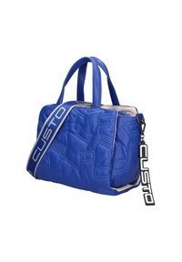 Sac à main en cuir matelassé bleu avec double poignée, une large bandoulière de marque, et une étiquette suspendue "CUSTO" sur la fermeture éclair.