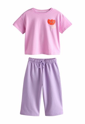 Rozā īsroku krekls ar sarkanu un baltu saldējuma grafiku, kombinēts ar lavandas krāsas šortiem ar elastīgu vidukli, abi izgatavoti no mīksta kokvilnas.