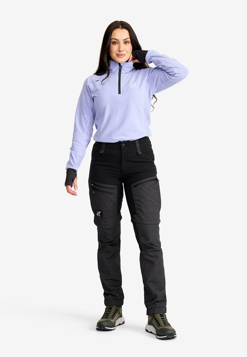 Ljuslila fleece halvdraget topp parat med svarta cargobyxor med flera fickor. Olivgröna ankelstövlar kompletterar outfiten.