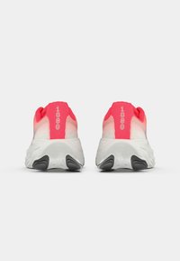 Des chaussures de course avec un dessus dégradé rose, présentant le numéro "1080" sur le talon, et une semelle blanche rembourrée avec des accents noirs.