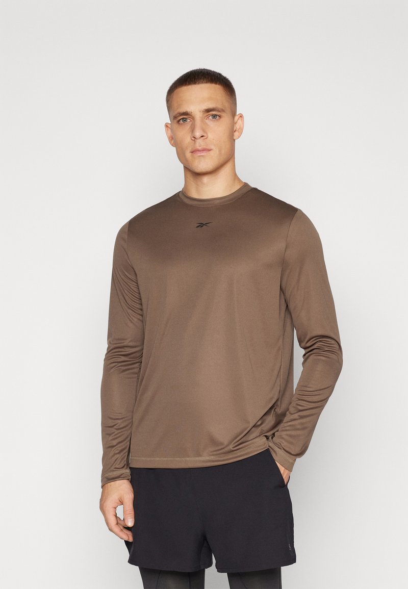 Brun langermet treningstrøye laget av glatt stoff, med rund hals og en liten logo på brystet. Kombinert med svarte shorts.