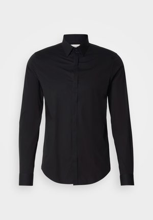 Chemise noire à manches longues avec col pointu, devant boutonné et ourlet arrondi. Fabriquée en tissu lisse sans motifs ni accents visibles.