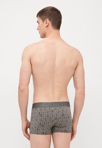 Szürke boxer nadrág geometrikus logó mintázattal, egyszínű derékrésszel. Az anyag lágynek tűnik, és testhezálló kialakítással rendelkezik.