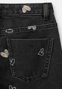 Schwarze Jeans aus Denim mit kleinen weißen bestickten Herzen und einer Gesäßtasche mit sauberer Verarbeitung. Der Stoff hat eine strukturierte Optik.