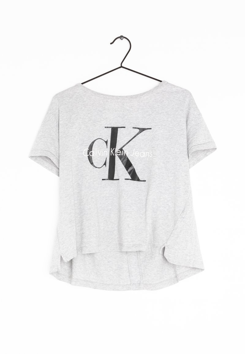 Helles graues T-Shirt mit kurzen Ärmeln aus Baumwolle, mit einem schwarzen "CK"-Logo und dem Text "Calvin Klein Jeans" auf der Vorderseite gedruckt.