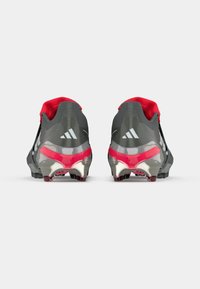 Football cleats featuring a black and gray synthetic upper with red accents, metallic silver detailing, and molded studded outsole for traction.