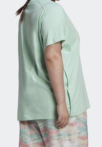 Mátově zelené trikotu s krátkým rukávem vyrobené z měkké bavlny. Nabízí uvolněný střih s bočními knoflíky a zakřiveným spodním lemem.