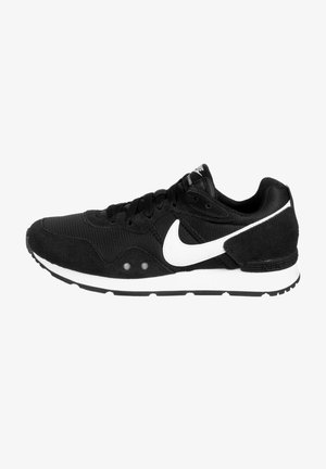 Zwarte sneaker van suede en mesh materialen, met een witte swoosh logo, vetersluiting, gestructureerde bovenkant en contrasterende witte tussenzool.