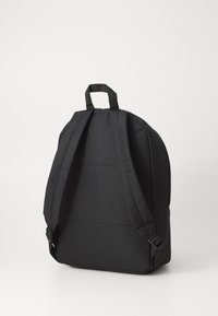 Sac à dos en tissu noir avec des bretelles réglables, une poignée supérieure, une forme structurée et une texture lisse. Pas de logos ni de motifs visibles.